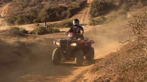 Karan riding an ATV down a dusty desert trail